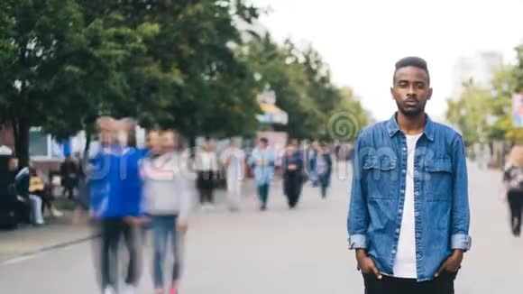 孤独的非裔美国男生手插口袋站在大城市的步行街上视频的预览图