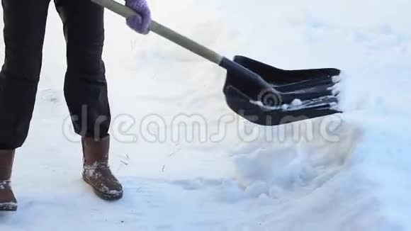 用铲子清理雪女人用铲子清理雪中的雪视频的预览图