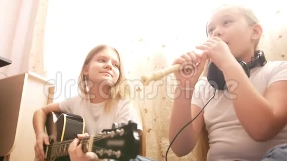 两名女青少年在家中坐在地板上演奏乐器吉他和长笛视频的预览图