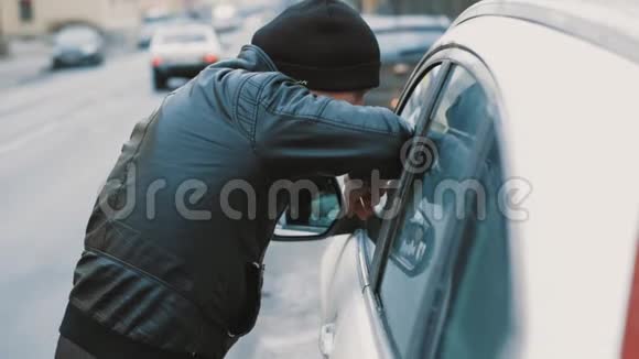 在城市里一个身穿黑色夹克戴着小帽子的男人靠在车窗上视频的预览图