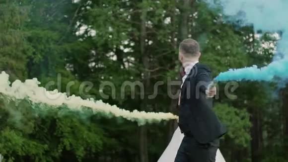 新婚夫妇在公园里一起旋转彩色烟雾慢动作视频的预览图