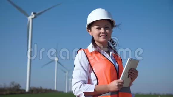 微笑着站在风电场旁边的女工程师视频的预览图