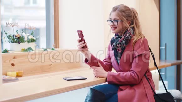 时尚的欧洲小女孩留着卷发一边用手机发短信一边开心地笑着视频的预览图