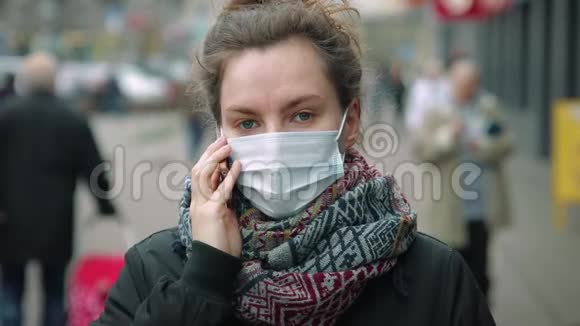 年轻女子在繁忙的街道上打电话戴着防护面具视频的预览图
