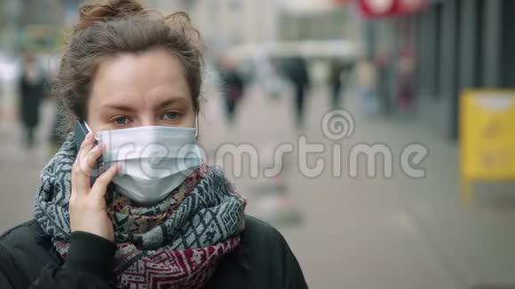 年轻女子在繁忙的街道上打电话戴着防护面具视频的预览图