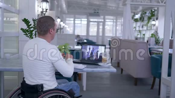 函授教育轮椅上的残疾人在笔记本上写笔记观看在线培训视频的预览图