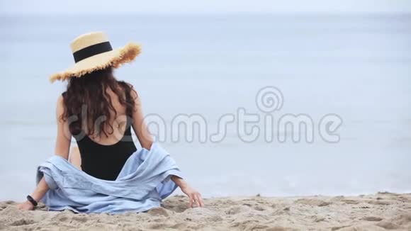 戴帽子的女孩坐在海滩上视频的预览图