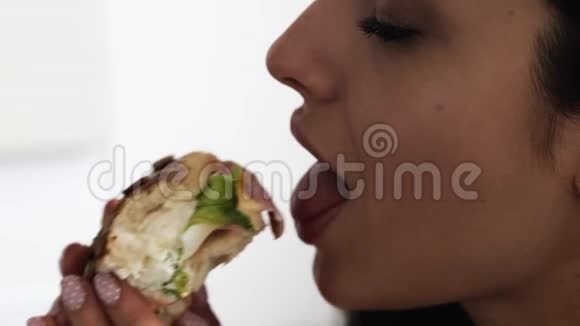 隔离期间年轻女子呆在家里女孩咬肥肉汉堡吃的慢动作白色隔离视频的预览图