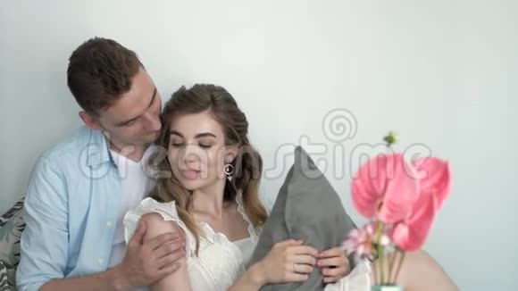 幸福浪漫的年轻夫妇在沙发上放松拥抱女孩带着一朵花视频的预览图