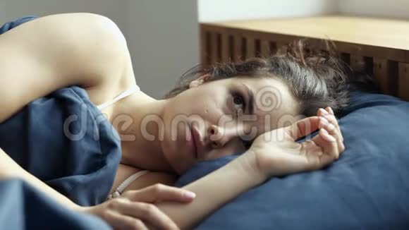 年轻女子在检疫期间呆在家里不高兴的女孩躺在床上不受噪音或早晨的影响遮住脸视频的预览图