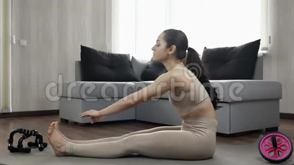 那个年轻女子在夸兰廷期间在家锻炼坐直身体前倾伸展至脚尖回去视频的预览图