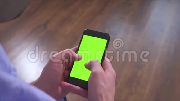 人类手拿着智能手机并使用它设备上的绿色屏幕输入电子键盘并向右滑动视频的预览图
