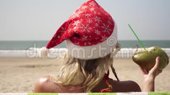 一个戴着圣诞帽的女人在海滩上晒日光浴海边的新年和圣诞节视频的预览图