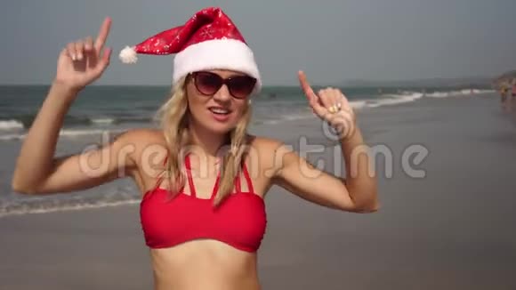 穿着红色泳衣和圣诞帽的美女在沙滩上跳舞视频的预览图