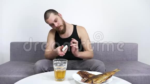 男人看电视喝啤酒和鱼孤独和酗酒视频的预览图