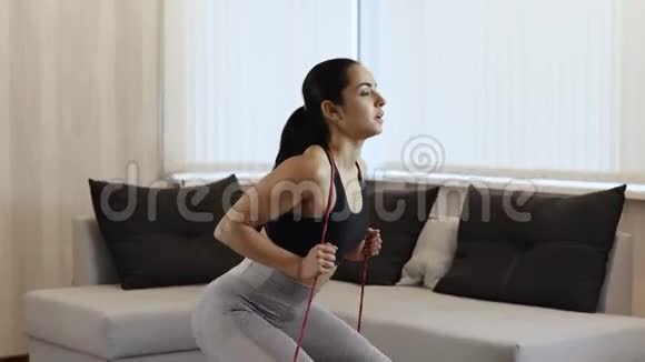 年轻女子在隔离期间在家锻炼做深蹲运动坐下站起来视频的预览图