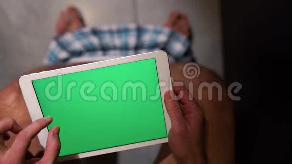 人坐在休息室的锅上手握平板电脑放大并滑动绿色屏幕单独在WC或厕所裤子视频的预览图