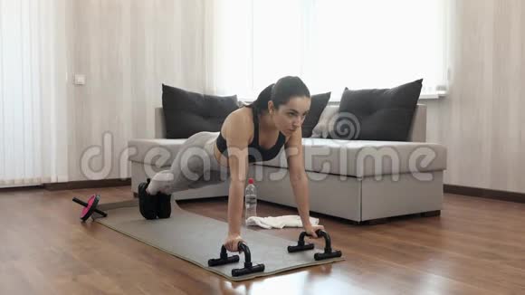 这个年轻女子在隔离期间在家锻炼强壮的女模特开始用器械做俯卧撑之后视频的预览图