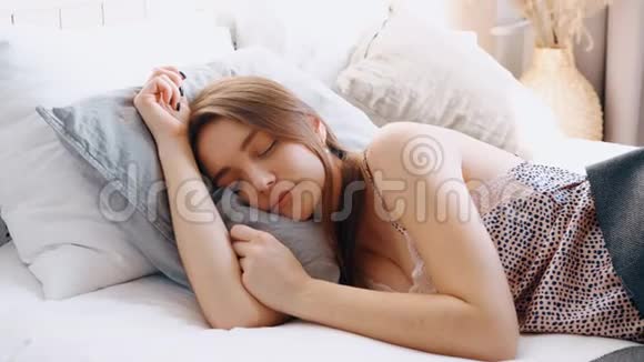闭上可爱的女孩醒来在舒适的床上阳光明媚的早晨公寓里的女孩睡在床上被墙后面的噪音激怒了视频的预览图