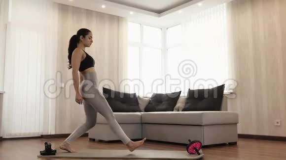 这个年轻女子在隔离期间在家锻炼苗条身材好的模特单腿站立做蹲式运动视频的预览图