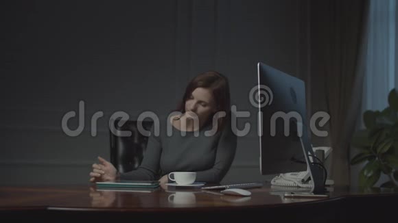年轻的女商人晚上在商务办公室工作平板电脑坐在舒适的办公室里喝咖啡的女人视频的预览图