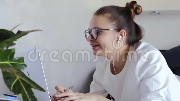 年轻女性导师在笔记本电脑上打电话在线聊天学生戴耳机通过电脑摄像头与老师交谈学习家庭隔离视频的预览图