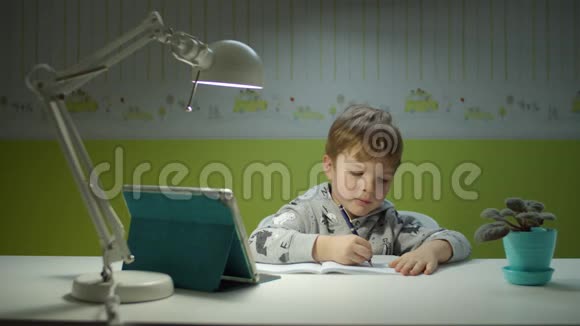 用平板电脑做在线作业的学龄前男孩坐在书桌边和孩子们一起在线学习的孩子视频的预览图
