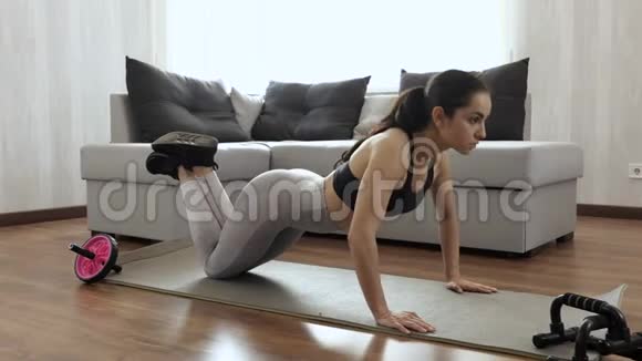 年轻女子在隔离期间在家锻炼站在膝盖上用强壮的手做俯卧撑照相机移动视频的预览图
