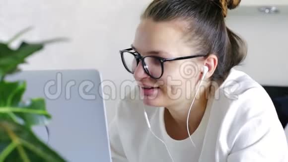 年轻导师在笔记本电脑上在线电话聊天戴牙套的女学生老师戴着耳机用摄像头说话学习家庭检疫视频的预览图