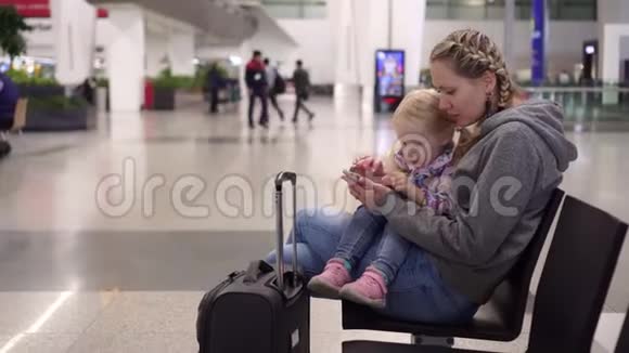 机场候机楼的家人在等待飞机时使用智能手机视频的预览图