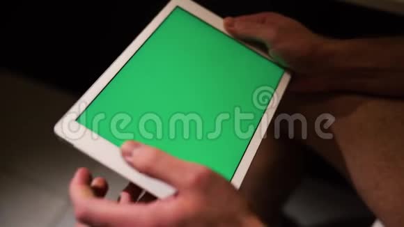 休息室坐在锅上的人侧视视频手拿着绿色屏幕的平板电脑玩视频的预览图