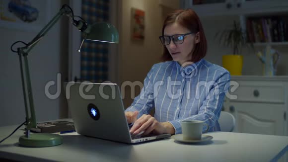 30多岁的年轻女性从家里完成工作关闭笔记本电脑并喝杯咖啡女人停下来享受视频的预览图