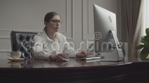 年轻的女商人在打电话布鲁内特在办公桌前工作班长坐在商务办公室的扶手椅上视频的预览图