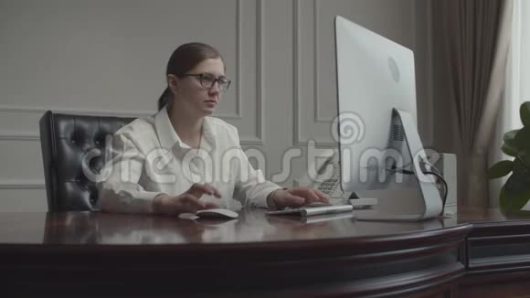 在办公桌上工作的年轻女商人在办公室的扶手椅上坐着显示器女局长要咖啡视频的预览图