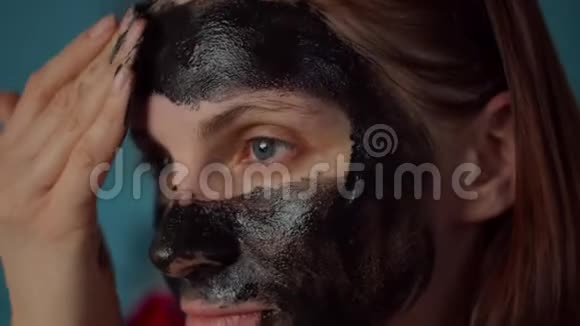 30多岁的年轻女性头上戴着黑色的箍脸上戴着黑色的化妆面具在家穿蓝色衣服的女人视频的预览图