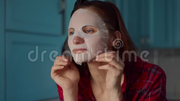 滑稽的30多岁的女人脸上戴着白色化妆面具在家里做鬼脸戴着蓝色面具做鬼脸的女人视频的预览图