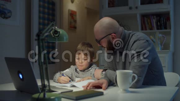 年轻的30岁的父亲和学龄前儿童在家做在线家庭作业在线教育过程父子家庭视频的预览图