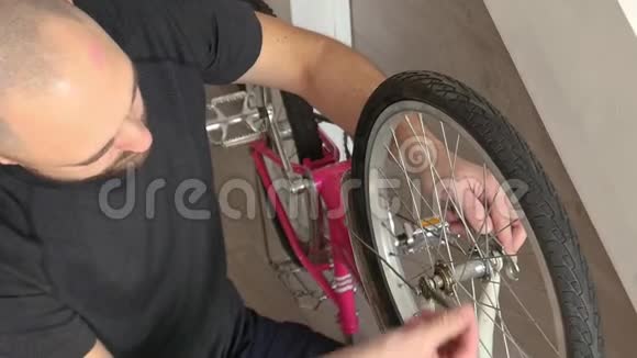 父亲修理他女儿的自行车在室内修理车轮和齿轮视频的预览图