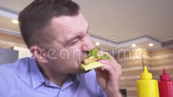年轻的休瑞男士提供美味可口的三明治他用满口的嘴吃完了在里面加点番茄酱视频的预览图