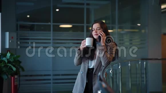 一个黑头发的漂亮女孩用智能手机聊天喝咖啡视频的预览图