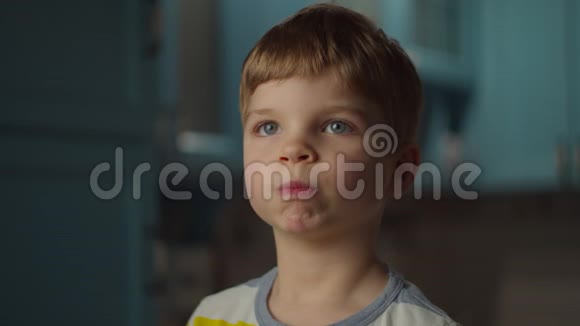一个学龄前金发男孩在嘴里玩橘子皮微笑的孩子嘴里有橘子水果橙色视频的预览图