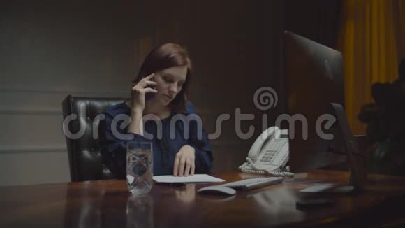 在夜间办公室工作的年轻女商人女人在牢房里说话看着桌子上的文件视频的预览图