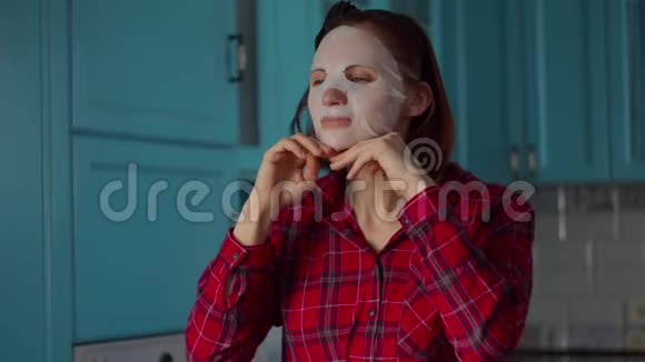 30多岁的年轻女性头上戴着黑色的箍脸上戴着白色的化妆面具在家穿蓝色衣服的女人视频的预览图