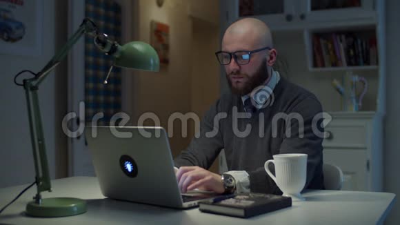 30多岁的年轻人在笔记本电脑上打字专注于家里的小工具屏幕有胡子的男人在家工作网上在线视频的预览图