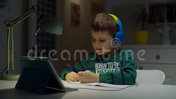一个戴彩色耳机的小学生使用平板电脑在家进行在线教育孩子喜欢做作业视频的预览图