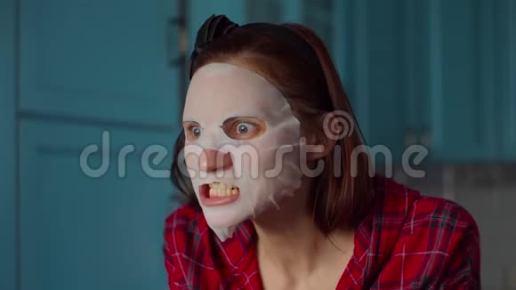 滑稽的30多岁的女人脸上戴着白色化妆面具在家里做鬼脸戴着蓝色面具做鬼脸的女人视频的预览图