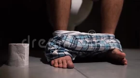 休息室里的男人坐在锅上在艰难痛苦的排便过程中脚上穿着裤子完成手后视频的预览图