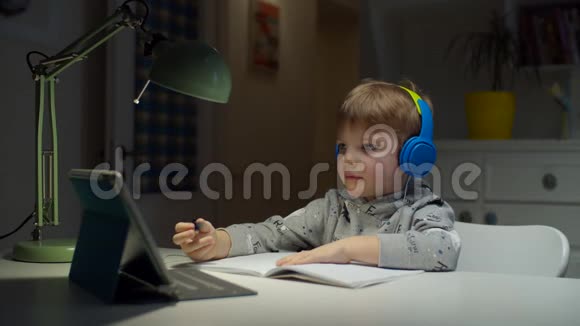 学龄前儿童彩色耳机使用平板电脑在线教育在家孩子喜欢上学视频的预览图