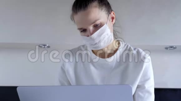 在家里用笔记本电脑在卧室里工作的年轻妇女戴着面罩冠状病毒隔离检疫视频的预览图