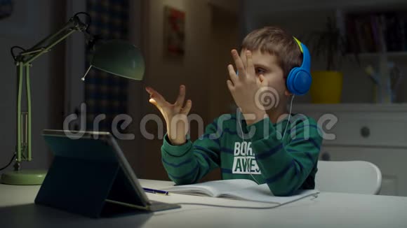一个戴彩色耳机的小学生使用平板电脑在家进行在线教育孩子喜欢做作业视频的预览图